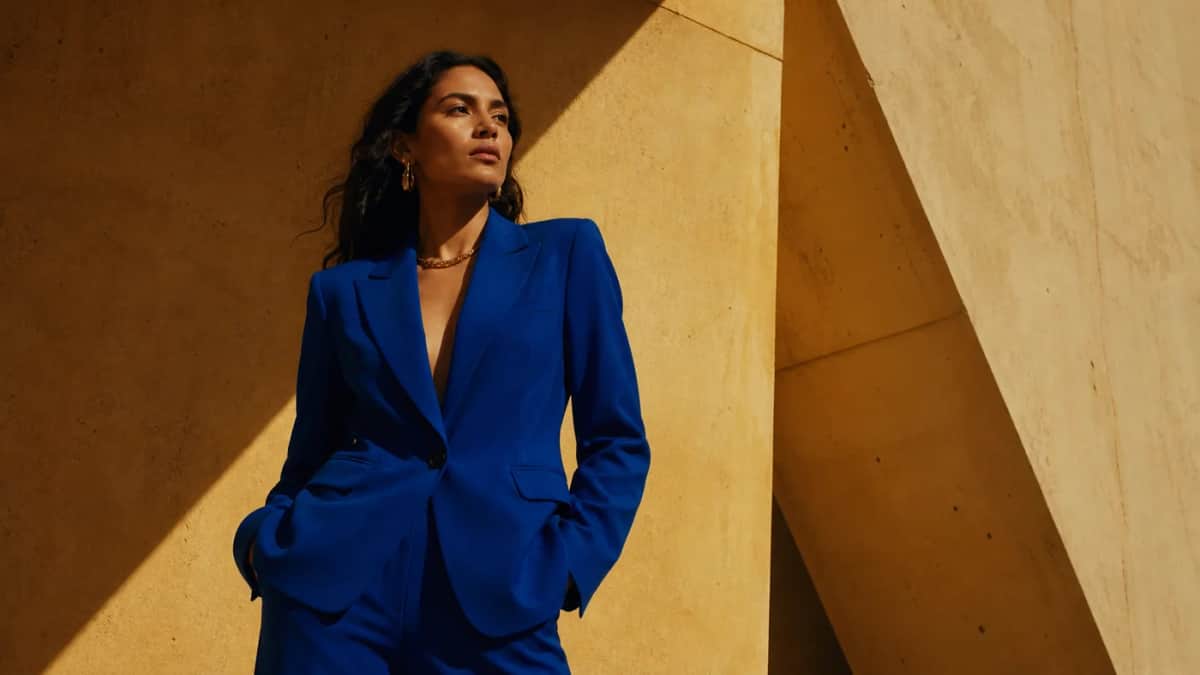 Concepto IA: modelo adulta con traje azul ante una arquitectura ocre