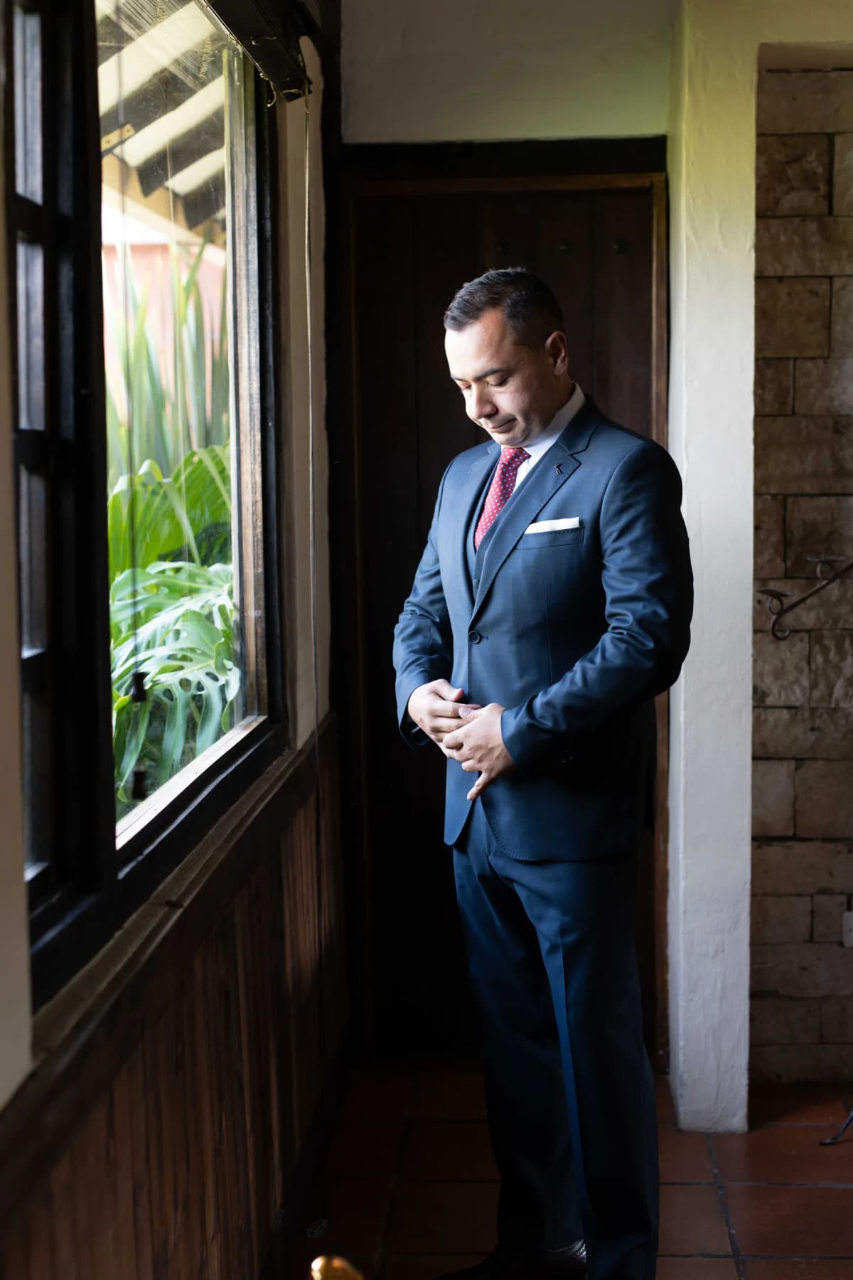 Retrato de novio junto a una ventana antes de la ceremonia