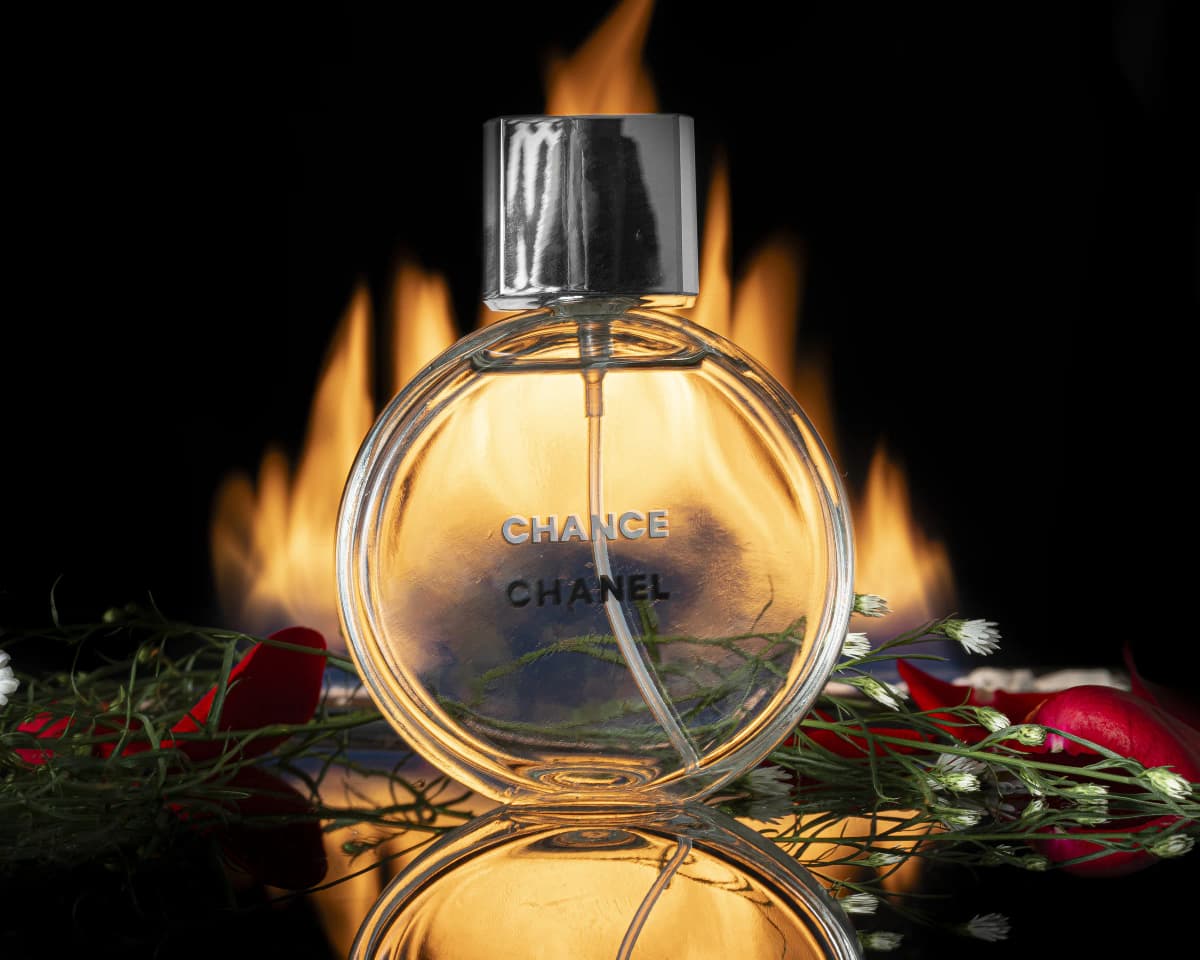 Perfume fotografiado de frente con fuego y rosas