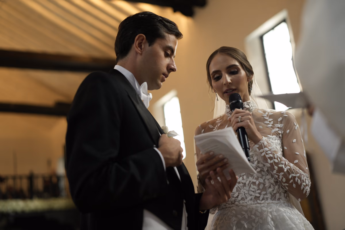 La novia lee sus votos con un micrófono mientras el novio la escucha
