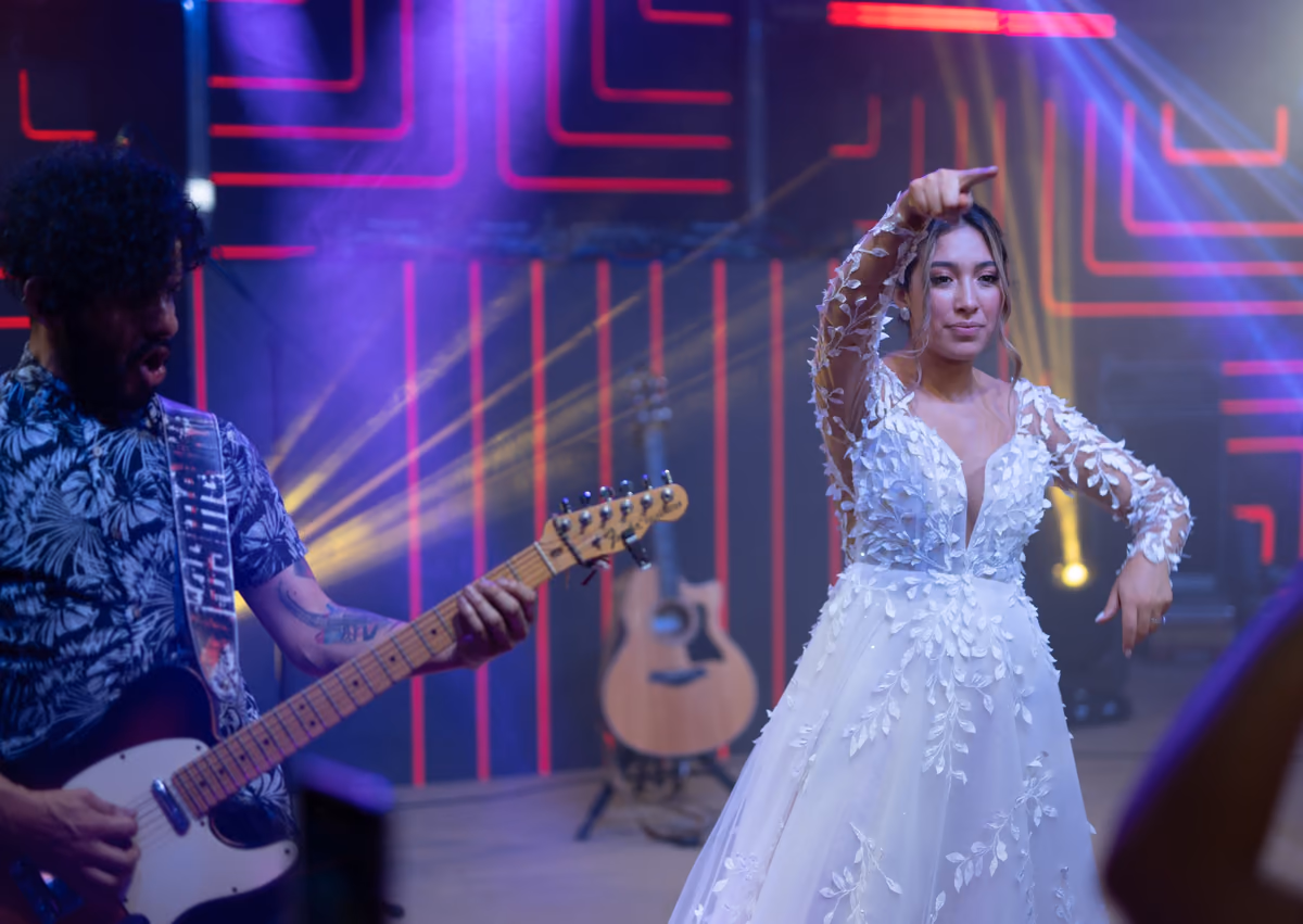 Nathaly baila en la tarima junto al guitarrista de la banda bajo luces de colores