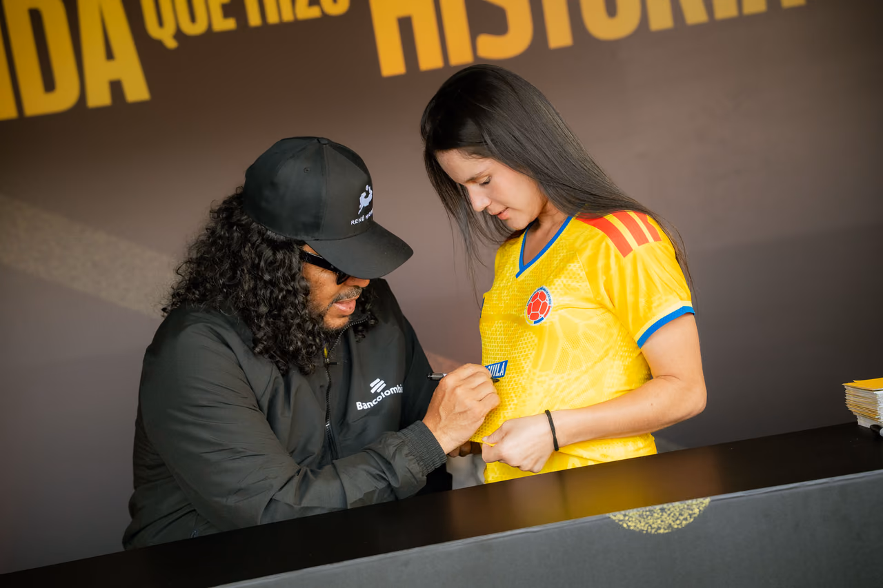 Firma de un autógrafo sobre la camiseta amarilla de una aficionada