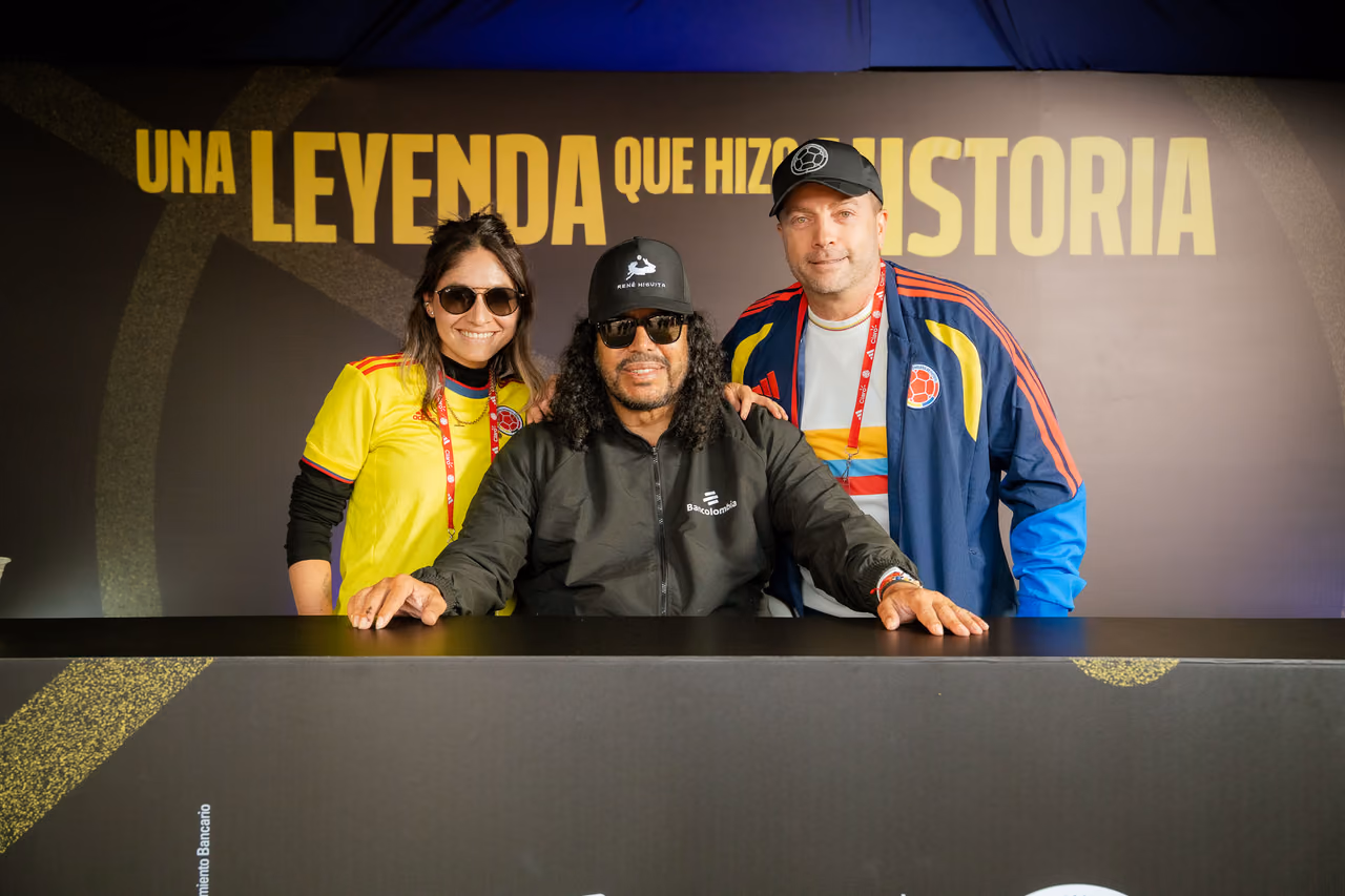 Dos aficionados posan con el invitado especial en la mesa de firmas