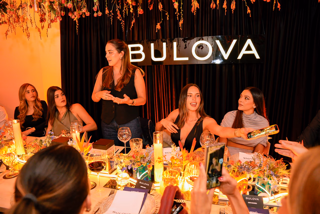 Anfitriona presenta la experiencia a los invitados de una cena de marca en una mesa larga