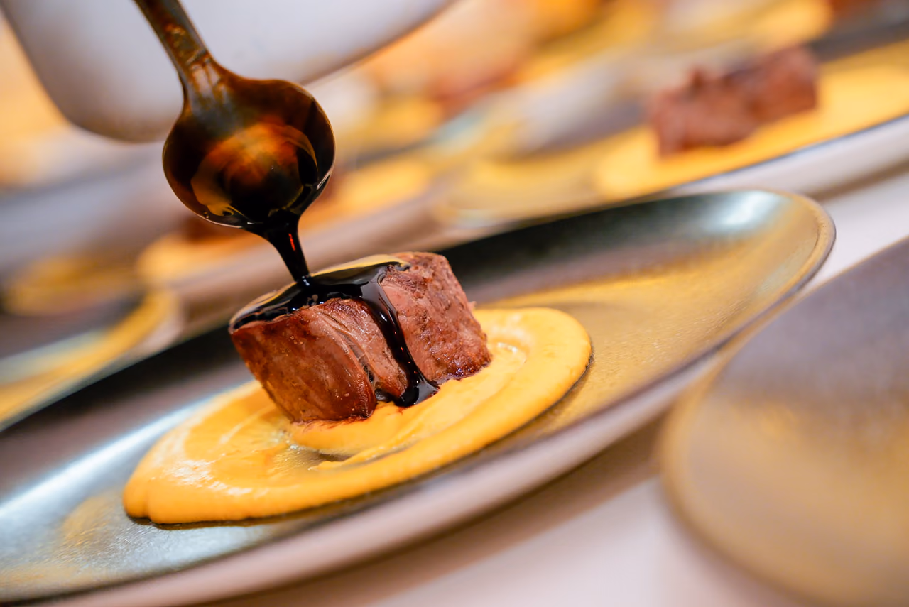 Un chef vierte salsa sobre un medallón de carne durante el servicio