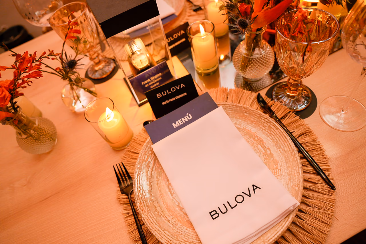 Puesto en la mesa con menú impreso, velas y tarjeta con el nombre del invitado