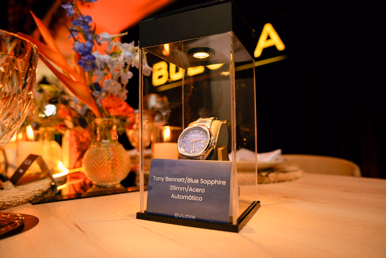 Reloj exhibido en una vitrina iluminada sobre la mesa del evento
