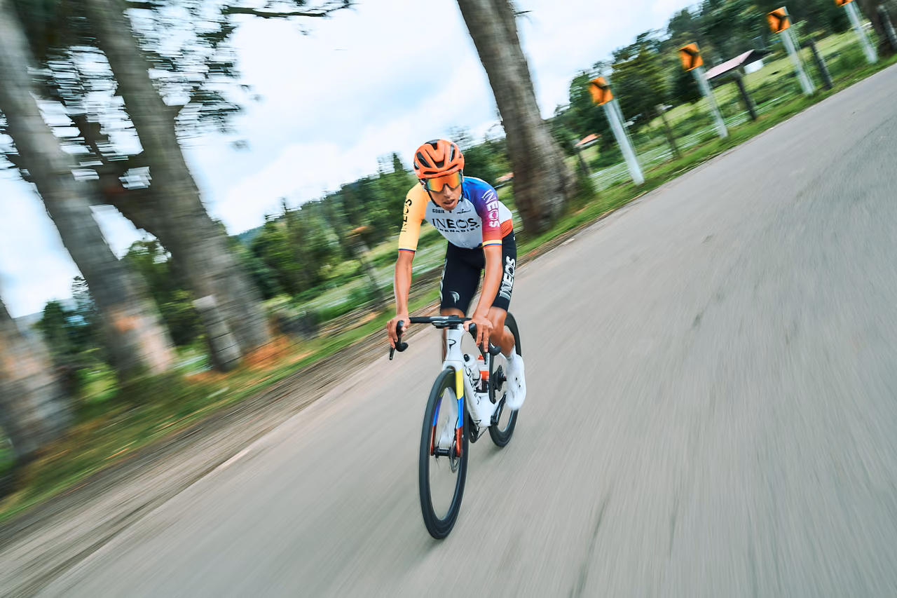 Ciclista profesional desciende por una carretera rural durante una rodada de marca