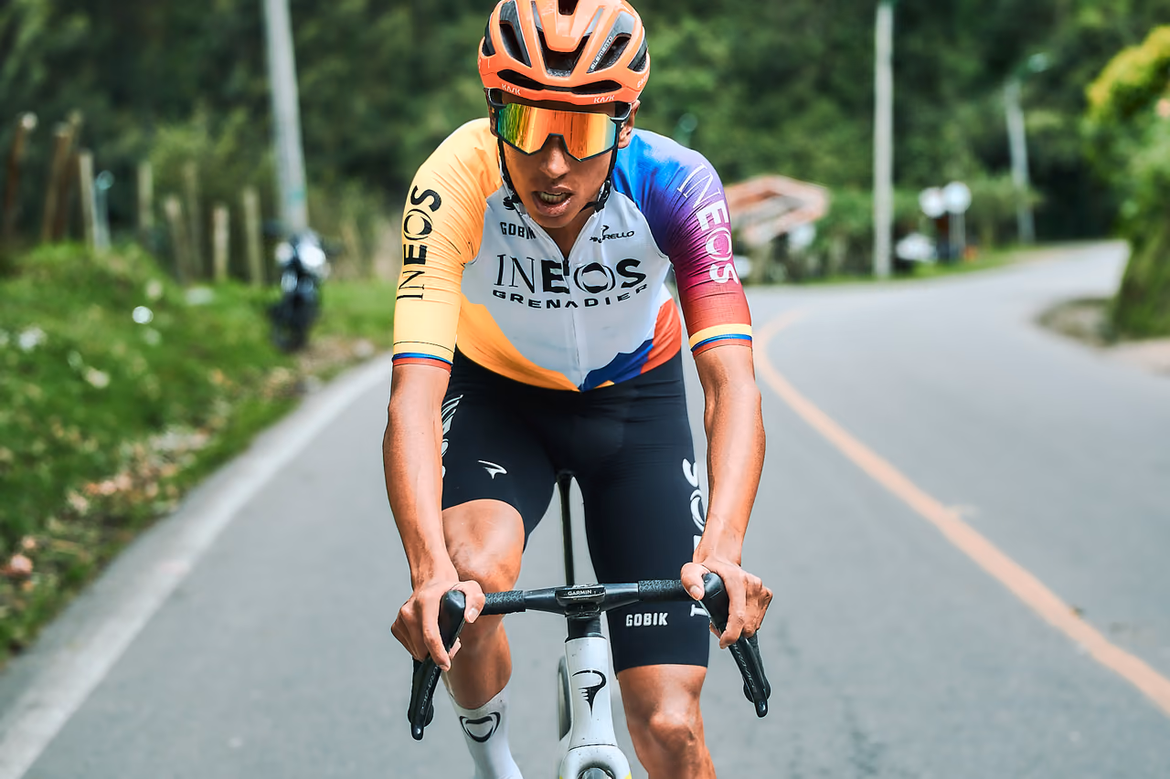 Ciclista profesional con casco naranja sube una carretera de montaña