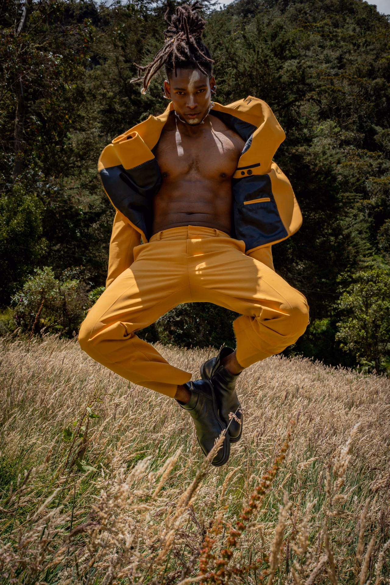 Modelo saltando con traje amarillo y botas negras en un campo de hierba