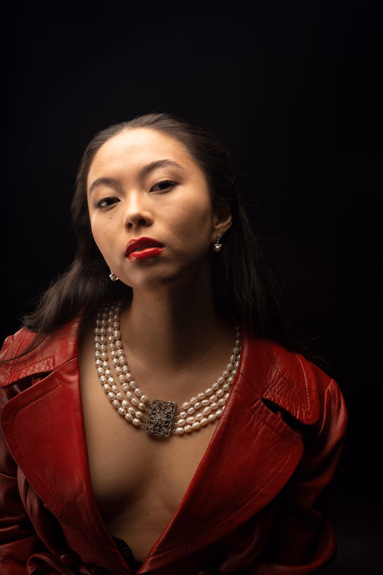 Retrato cercano con collar de perlas y chaqueta roja sobre fondo negro