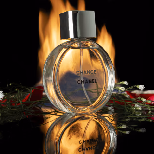 Perfume fotografiado entre fuego y reflejos