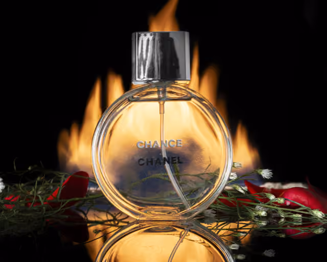 Perfume fotografiado de frente con fuego y rosas