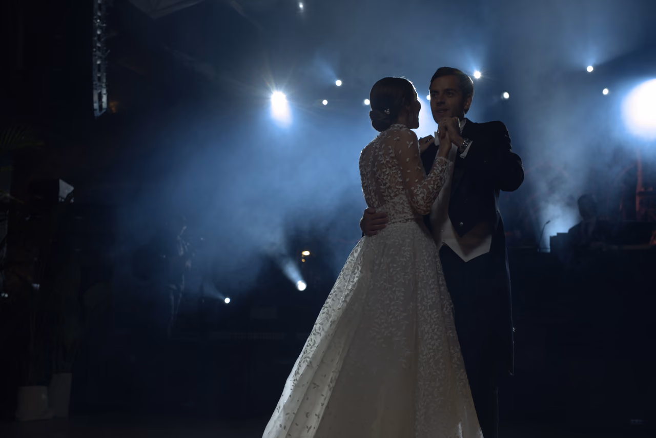 Pareja de novios bailando frente a luces azules y humo de escenario
